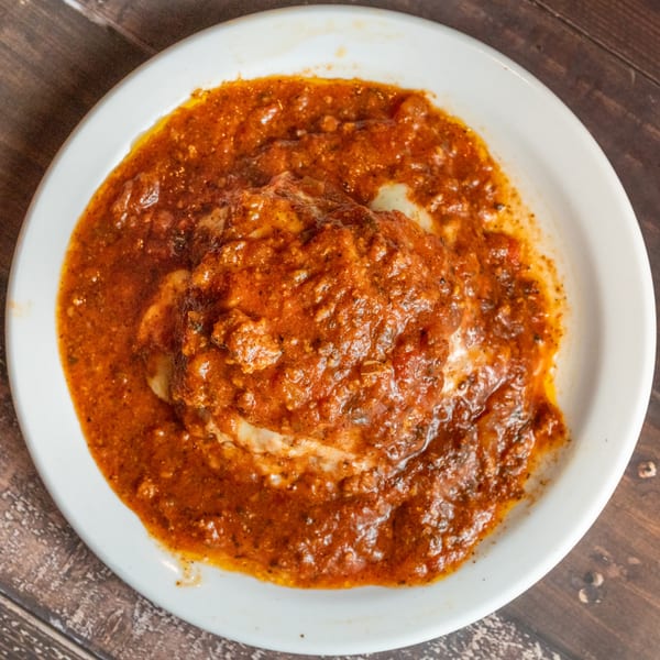 Alesi Pizza House's baked Italian dish, possibly lasagna or ravioli, covered in a rich red sauce.
