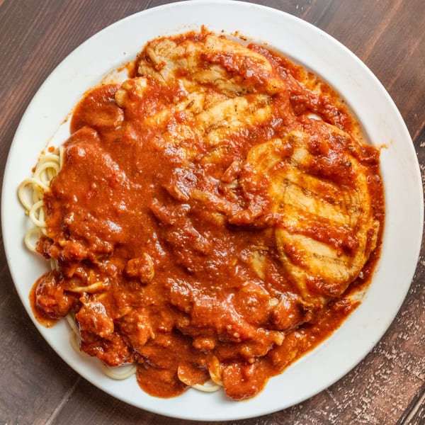 Alesi Pizza House's chicken parmesan with spaghetti, covered in rich red sauce on a white plate.